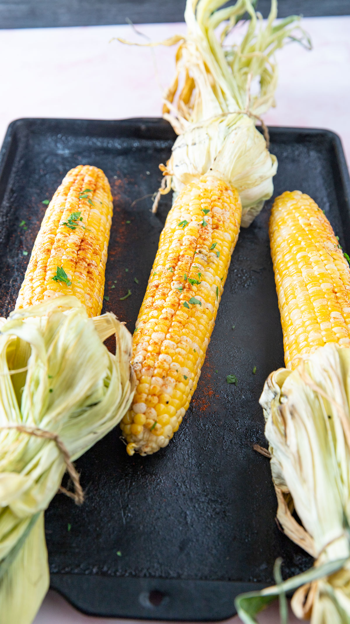 Smoked corn with the husks left on and tied at the top.