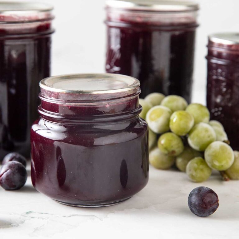 Jars of grape jelly with fresh grapes
