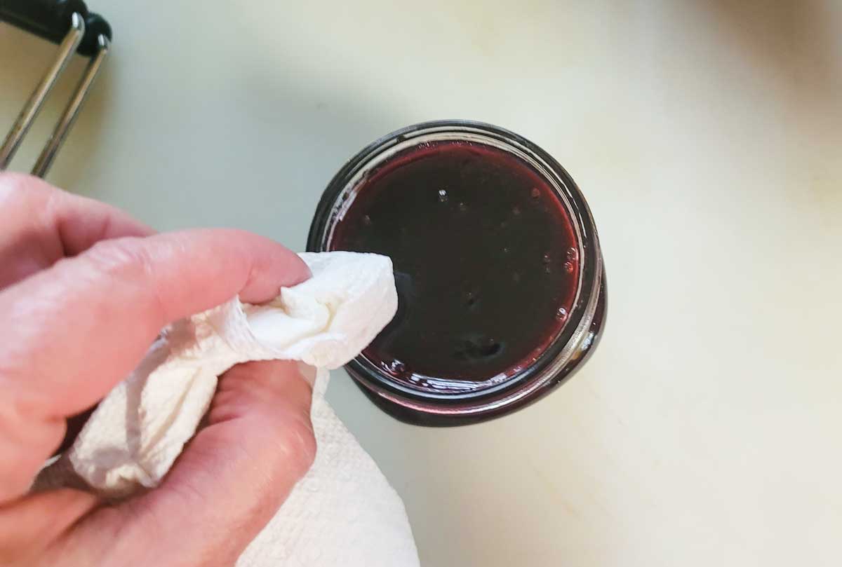 Wiping the rim of the jar with a damp paper towel.