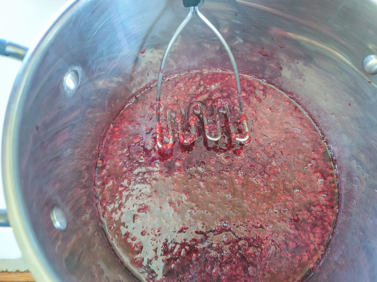 Mashing grapes with a potato masher.