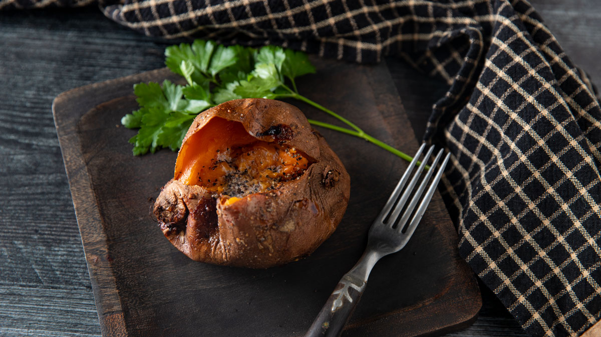 Sweet potato with parsley on a wooden plate.