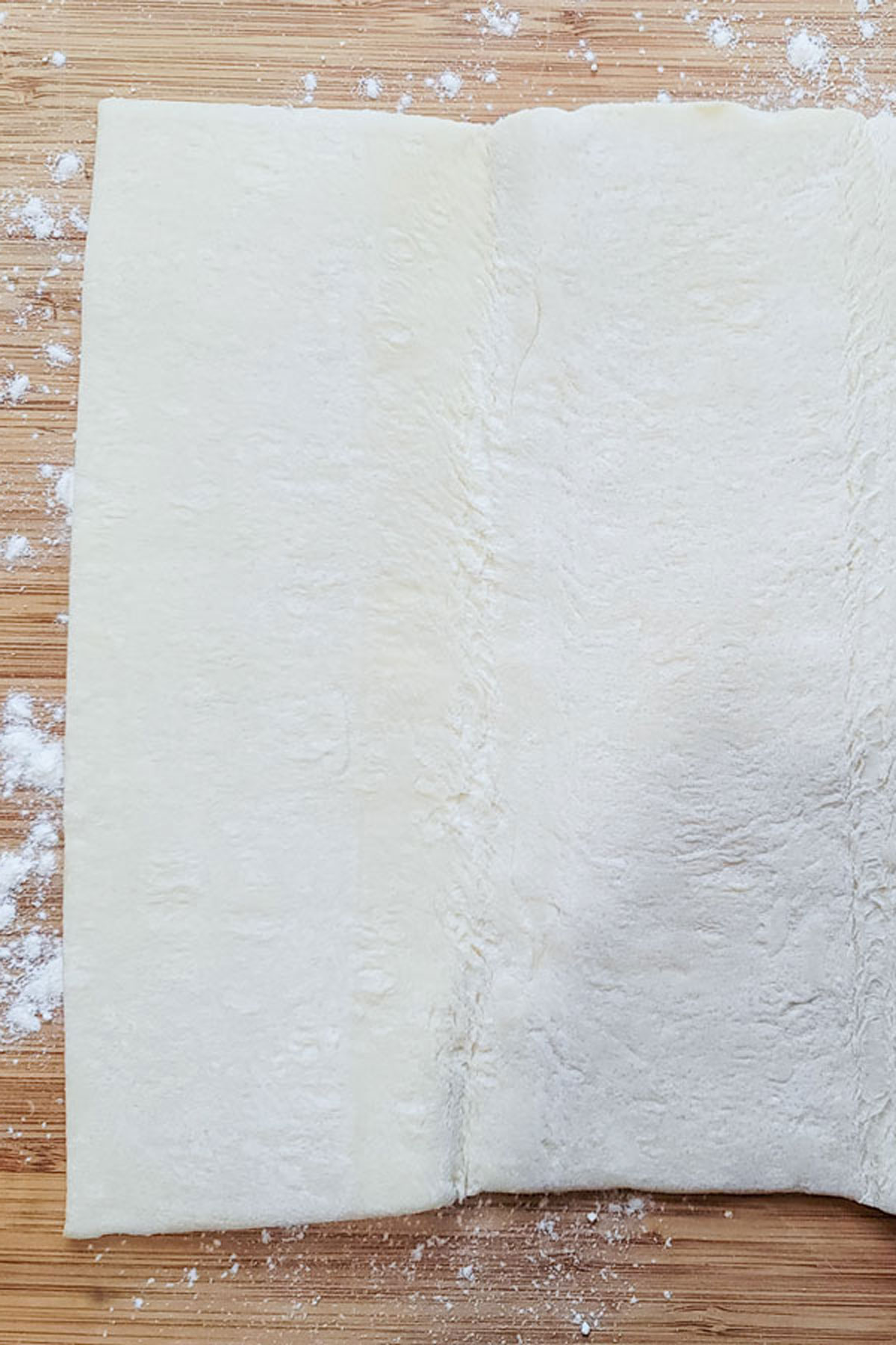 Puffed pastry and flour on a wooden board.