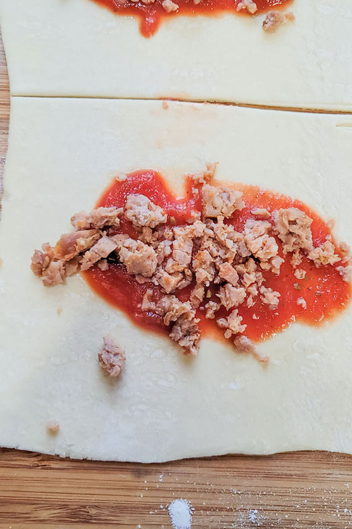 Sauce and meat on a pastry square.
