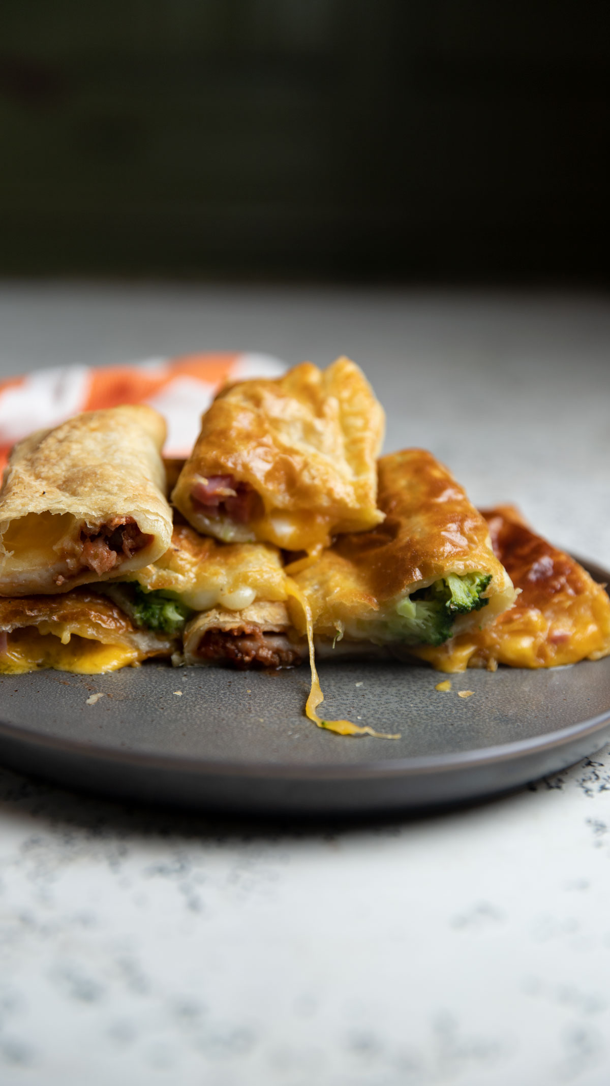 Air fryer broccoli filled hot pockets on a gray plate with oozing cheese.