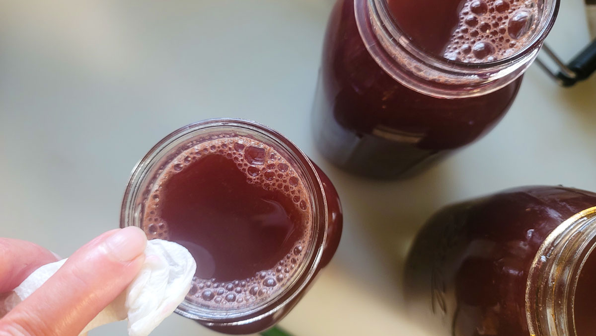 Wiping the jar rim with a paper towel.
