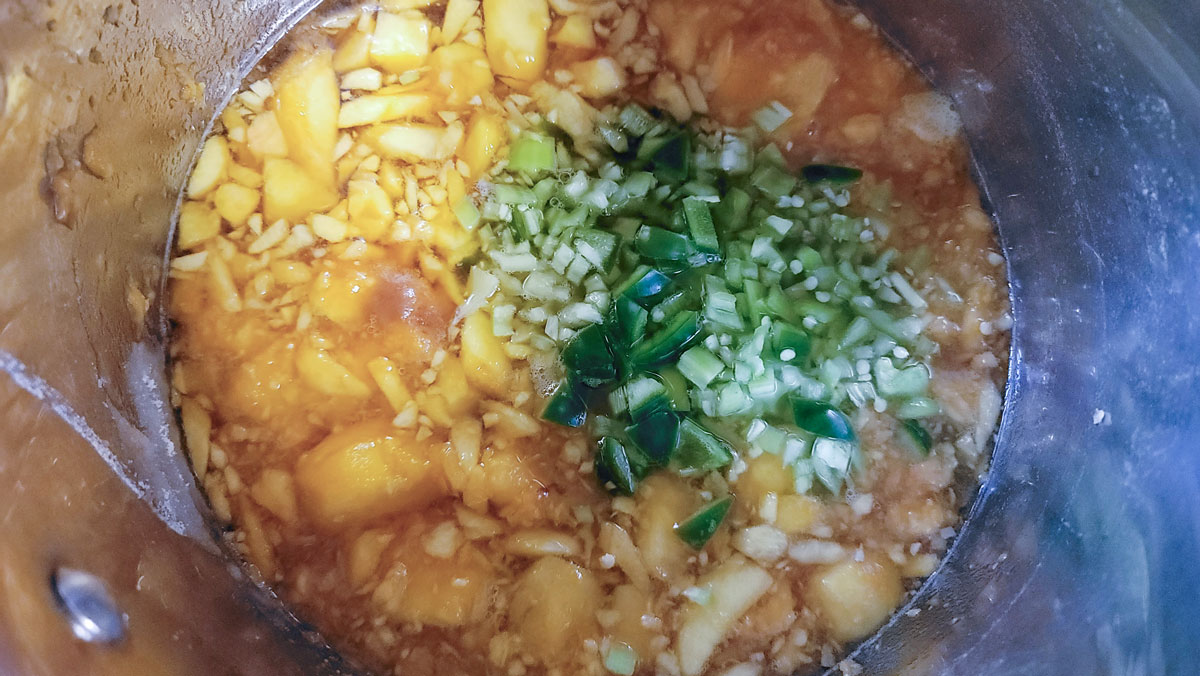 Crushed peaches and peppers in a large saucepan.