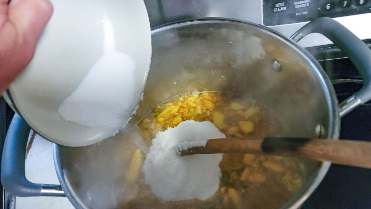 Adding sugar to the peach mixture.