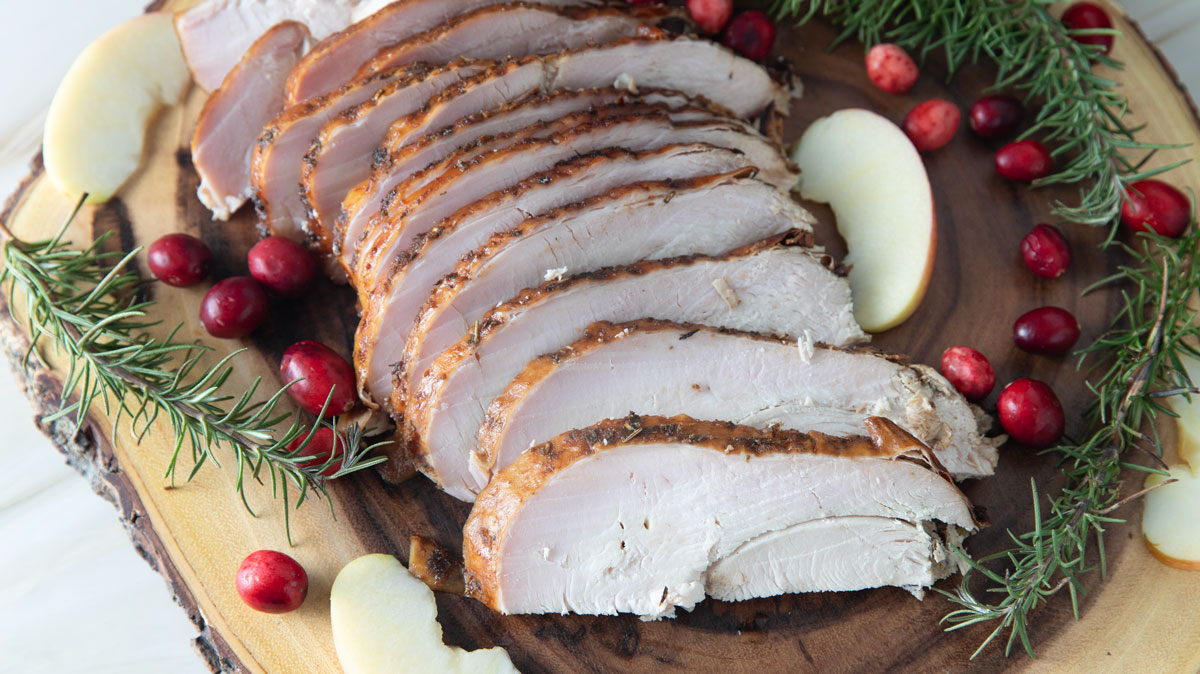Sliced smoked breast on a wooden slab.