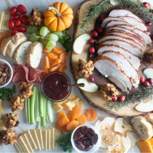 Sliced turkey and colorful fruits on a fall charcuterie board.
