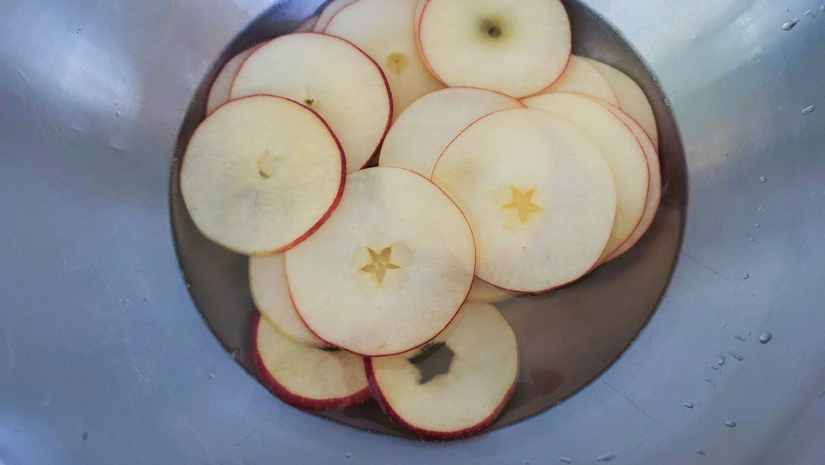 Apples in a bowl with a soaking solution.
