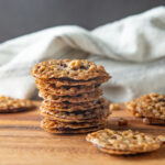 A stack of lace cookies on a wooden board.