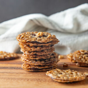 A stack of lace cookies on a wooden board.