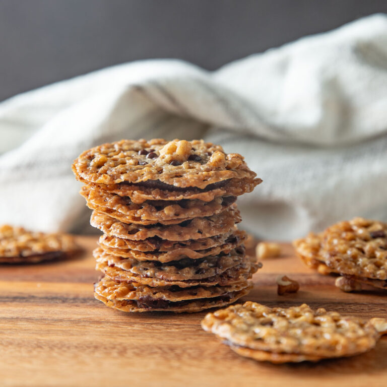 A stack of lace cookies on a wooden board.