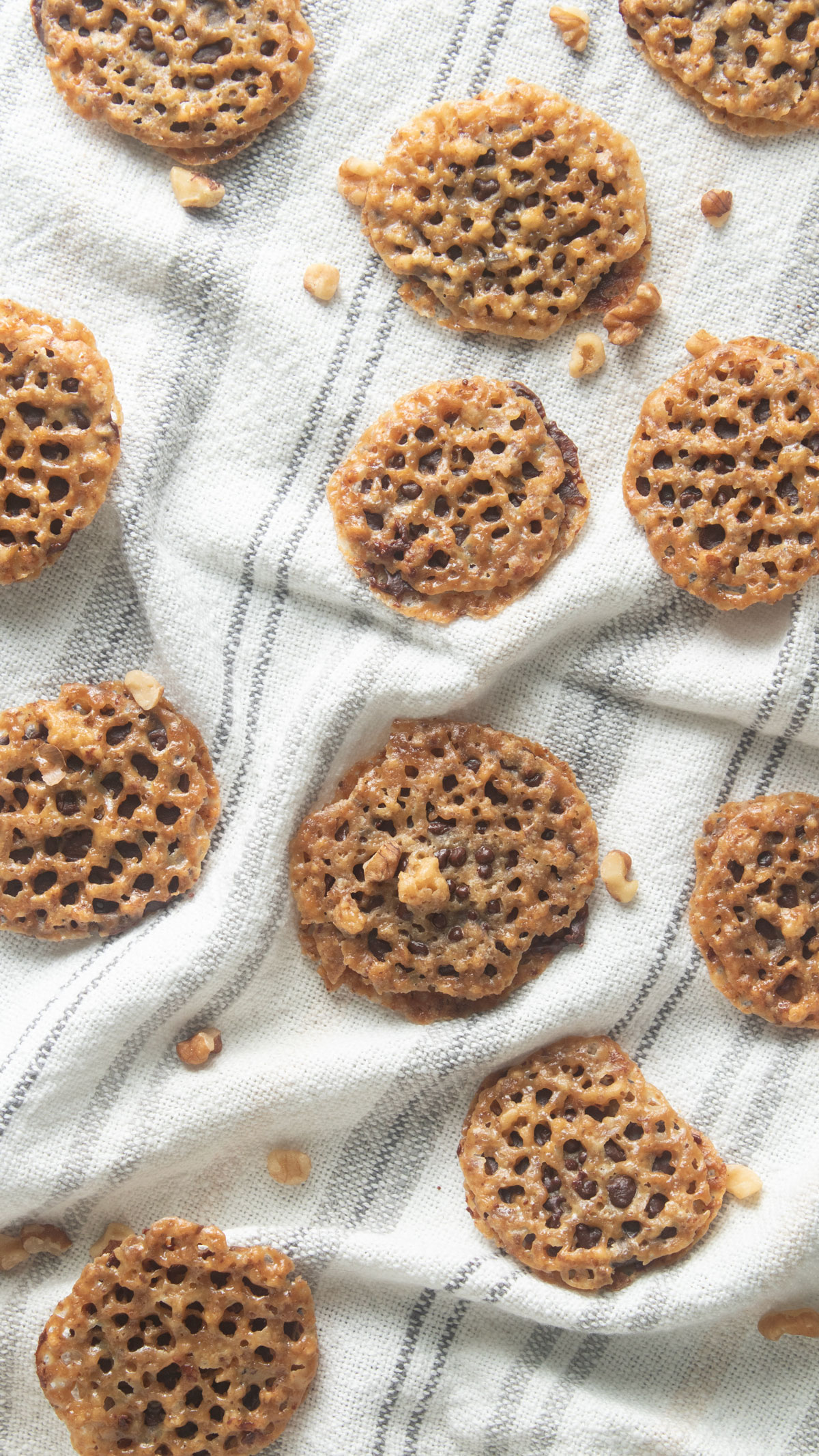 Lace cookies scattered on a white tea towel.