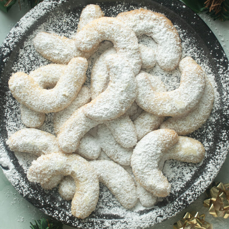 Large plate of Viennese Crescents sprinkled with powdered sugar.