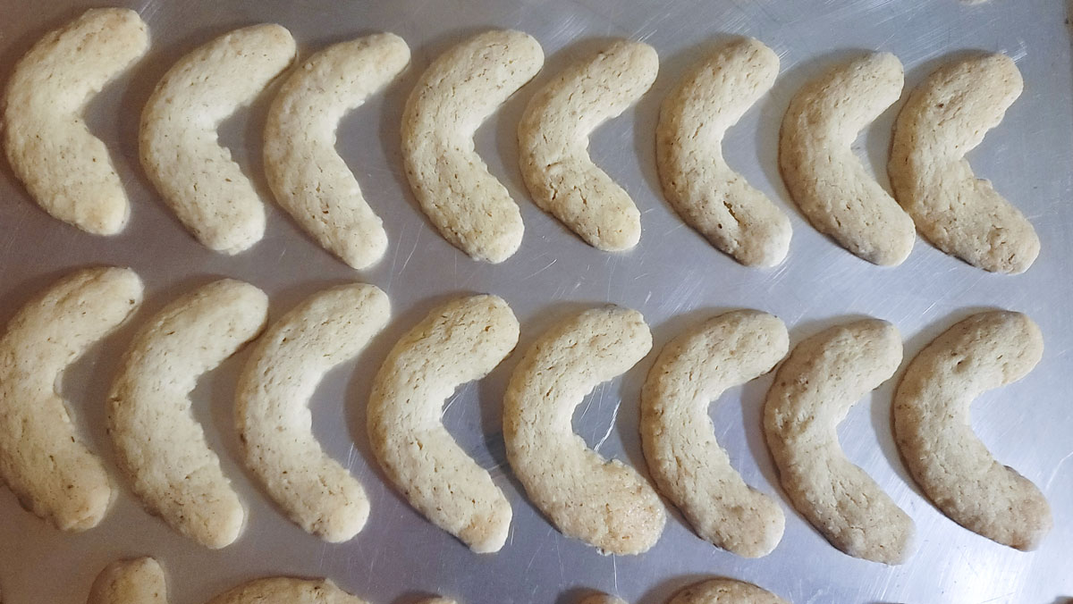 Baked crescent-shaped cookies on a cookie sheet.