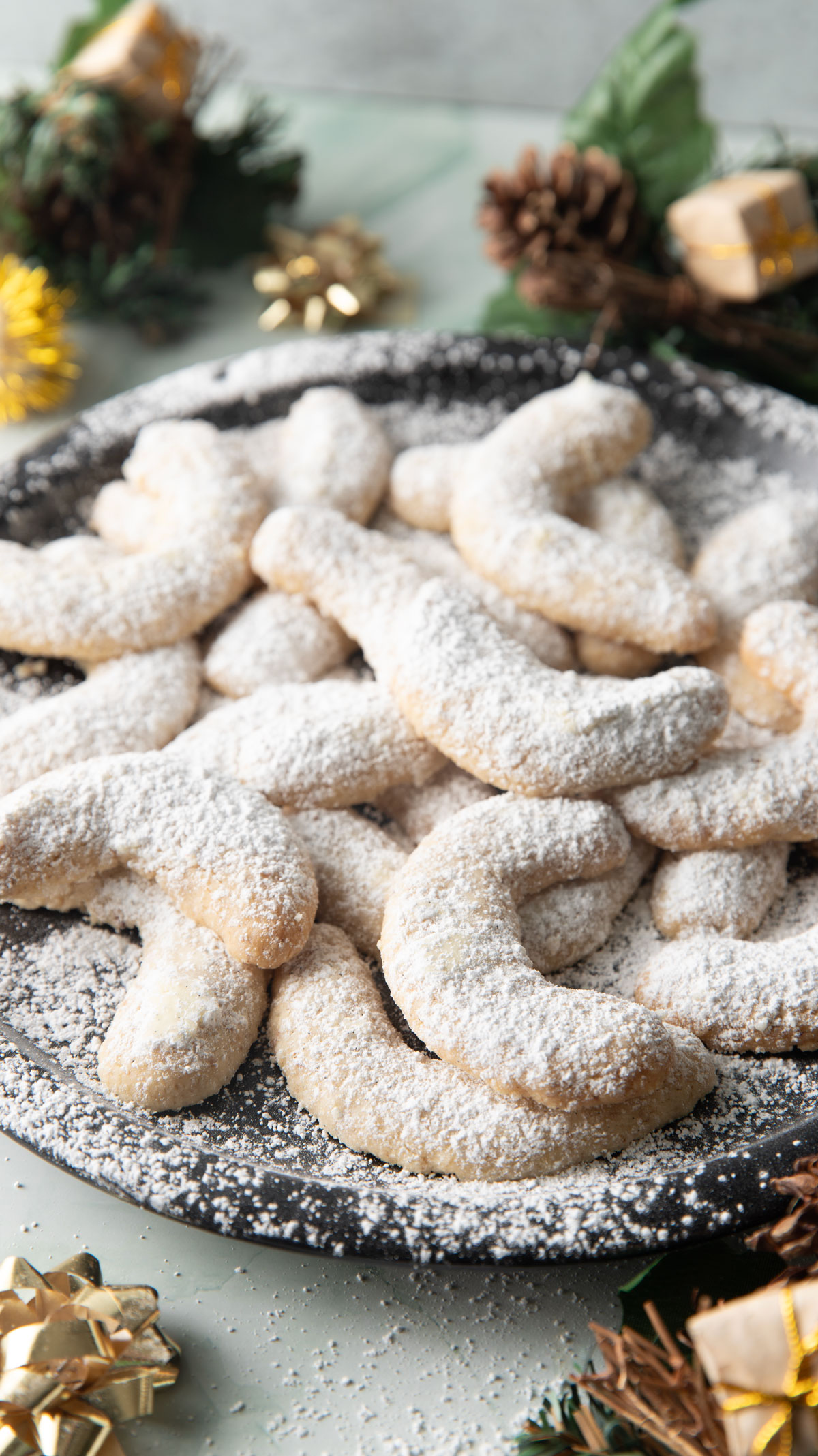 Viennese crescents on a black plate with Christmas decorations.