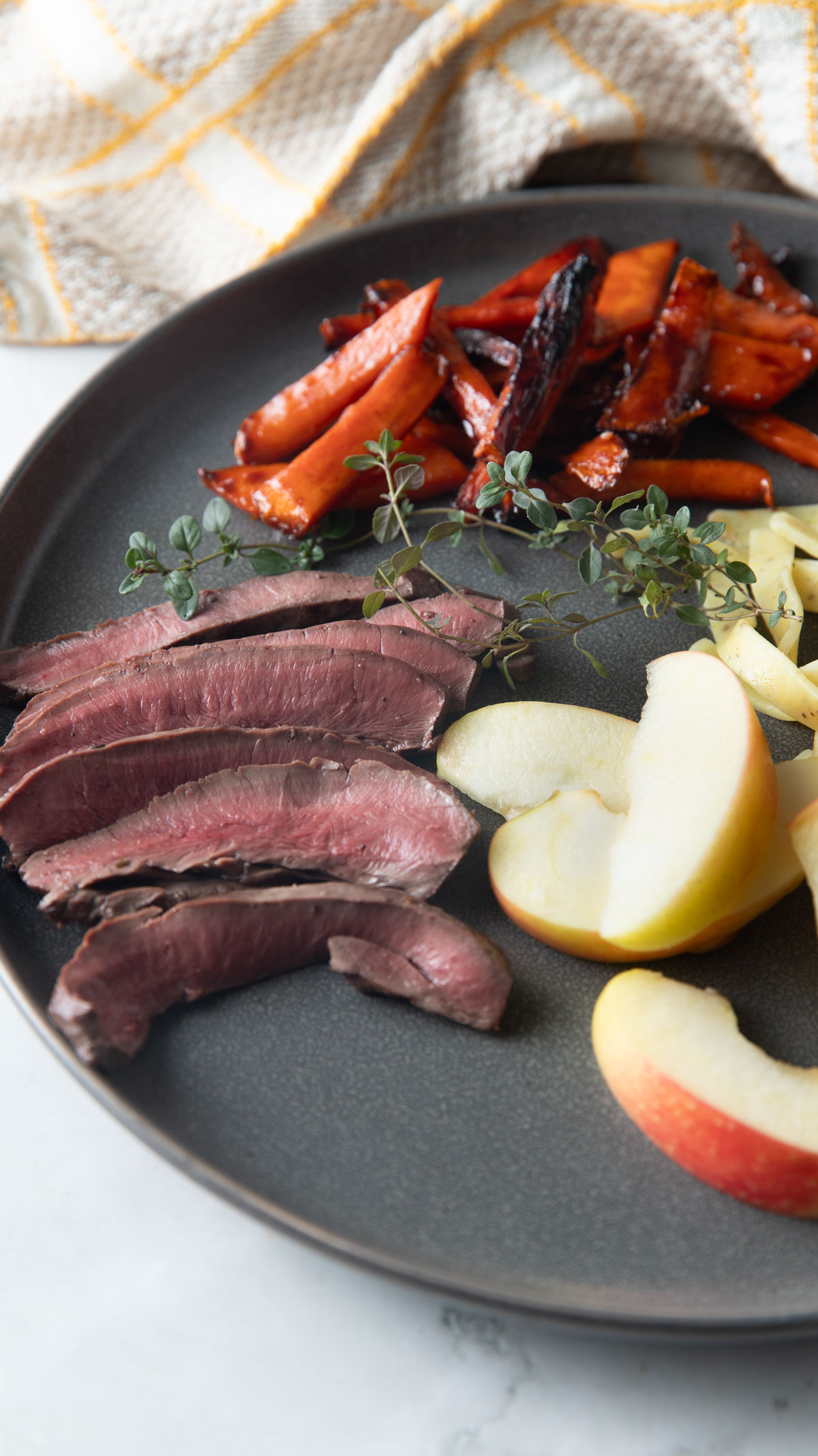 Sliced deer heart steaks on a gray plate with sides.