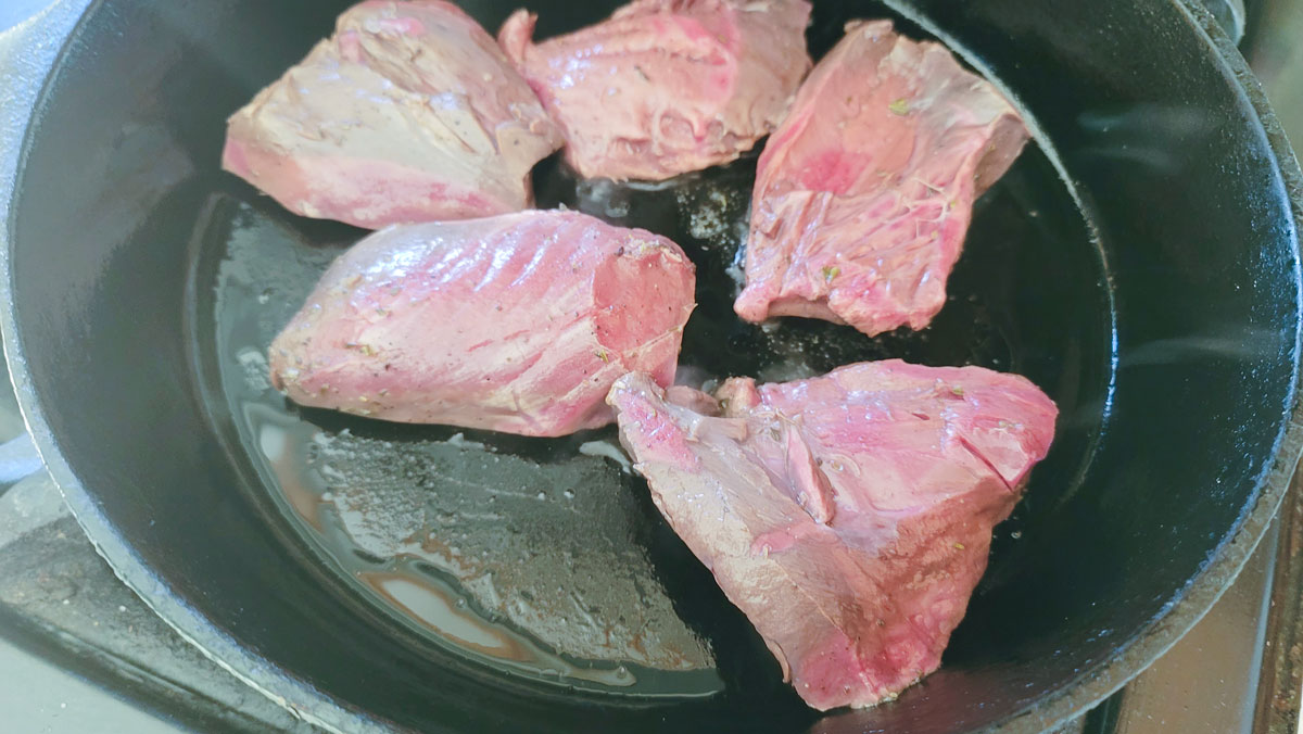 Searing the steaks in a cast iron pan.