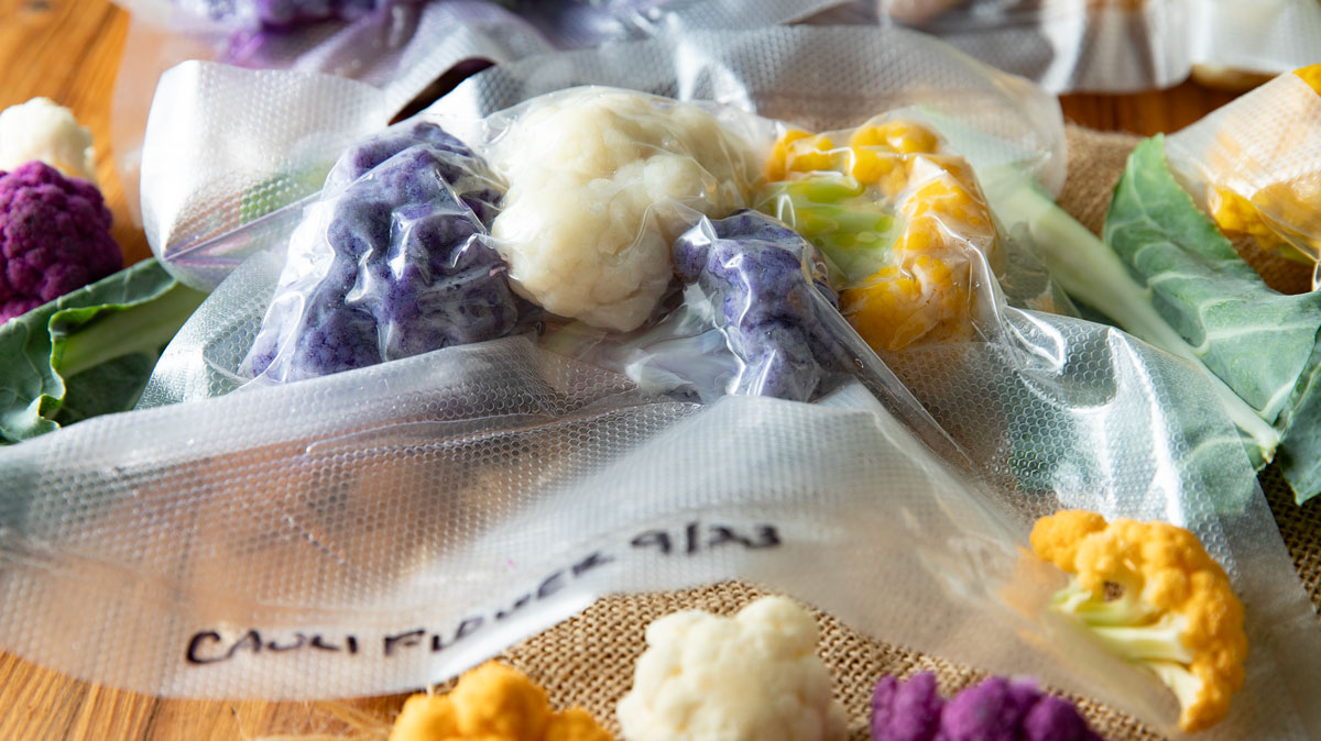 Bags of frozen cauliflower with fresh cauliflower in the photo.