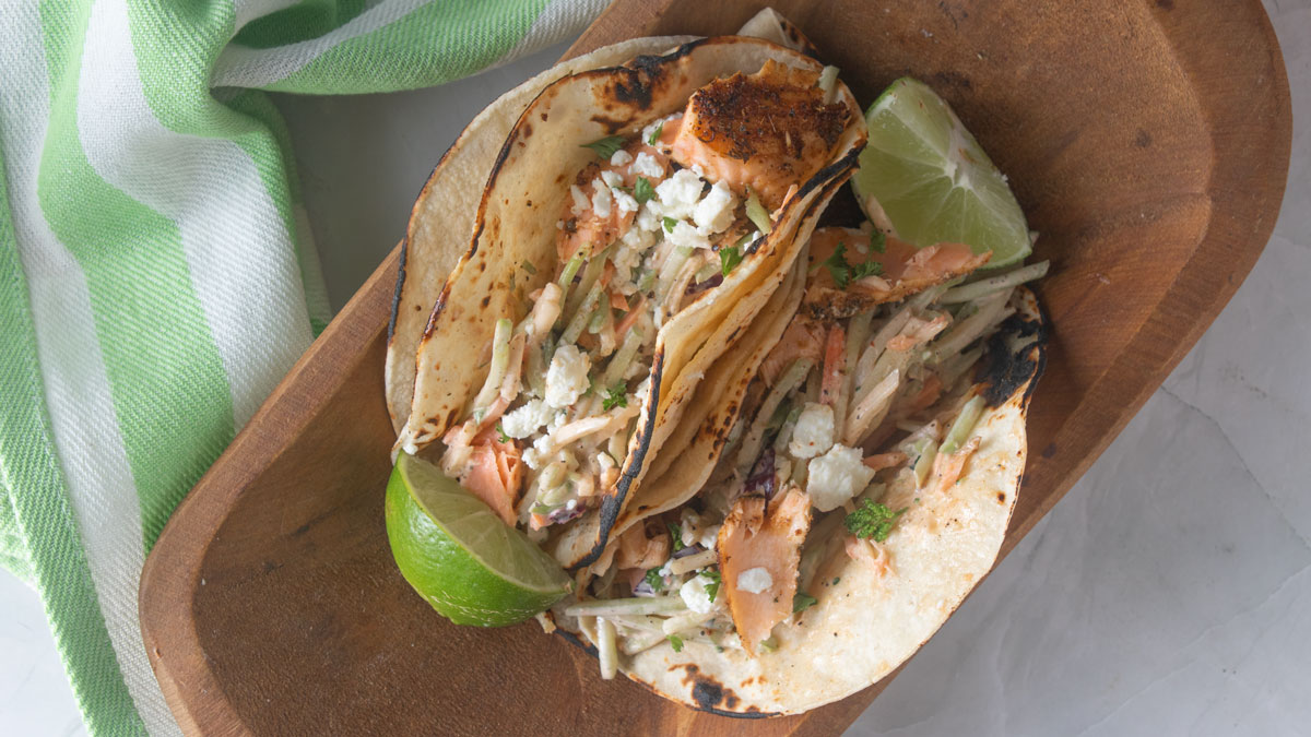 Salmon tacos in a wooden serving bowl.