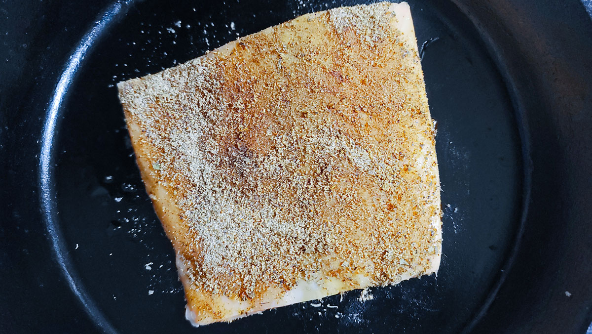 Coated Salmon in a cast iron pan.