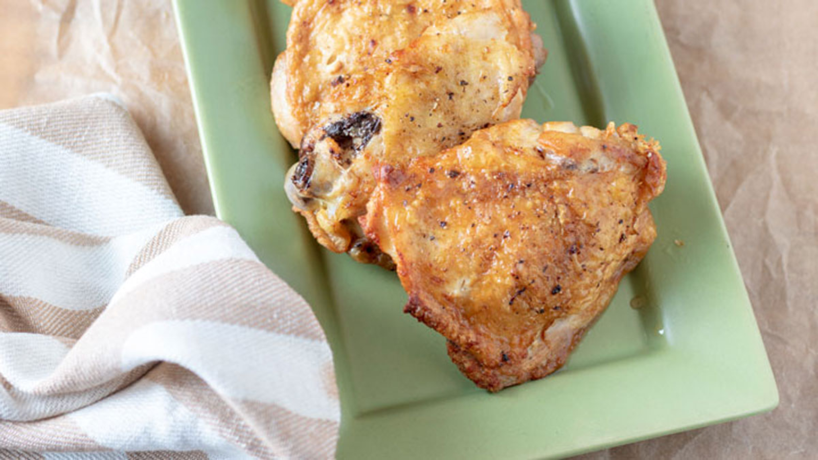 Two fried chicken thighs on a plate.