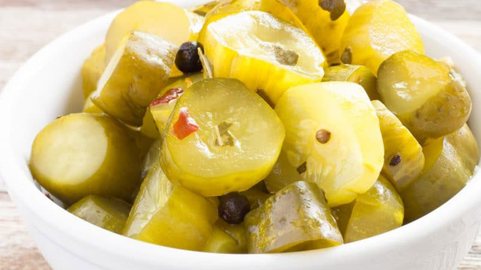 Candied pickles piled in a white bowl.