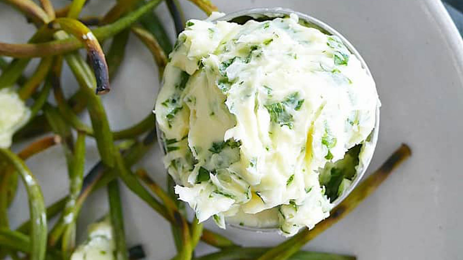 Charred scapes with a bowl of parsley butter.