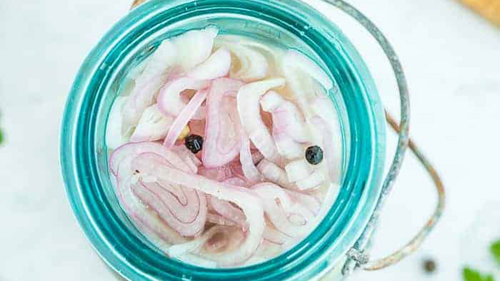 Pickled shallots in a blue jar.