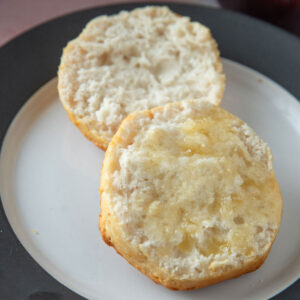 Air fryer biscuit cut in half slathered with butter.