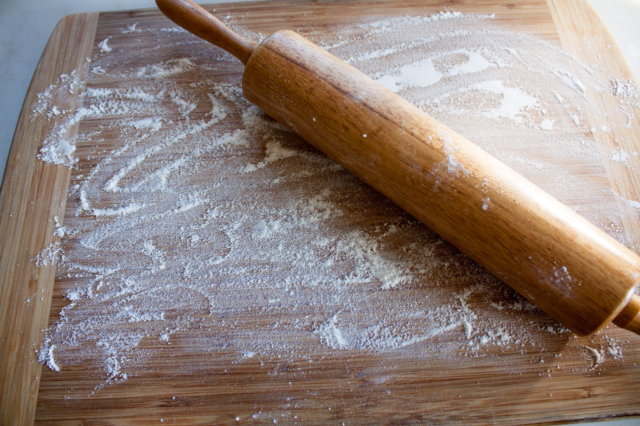 Cutting board with flour and a rolling pin.