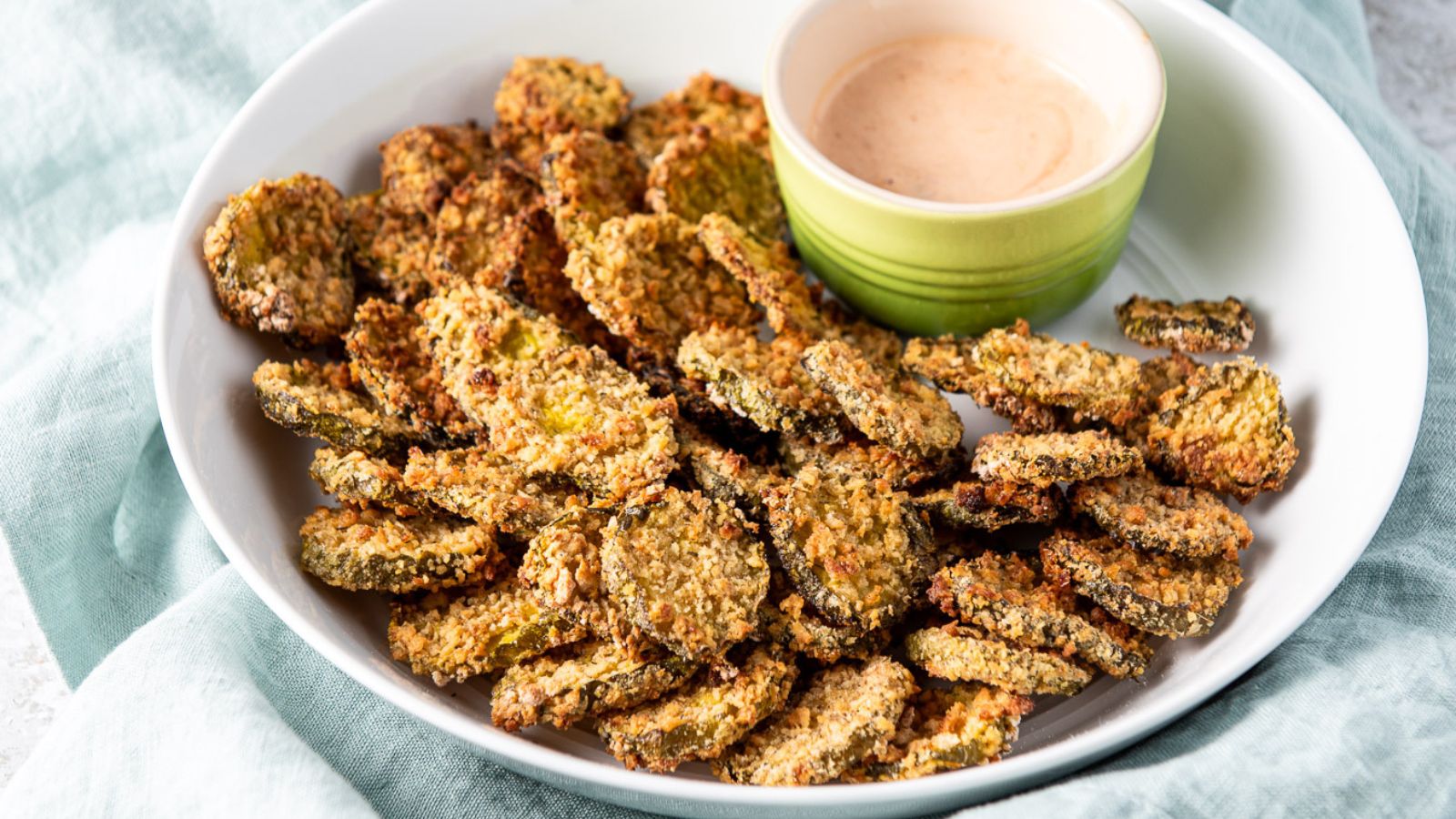 Air fryer pickles arranged on a bowl with dipping sauce.