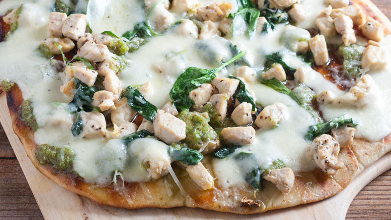 Chicken florentine pizza on a wooden peel.