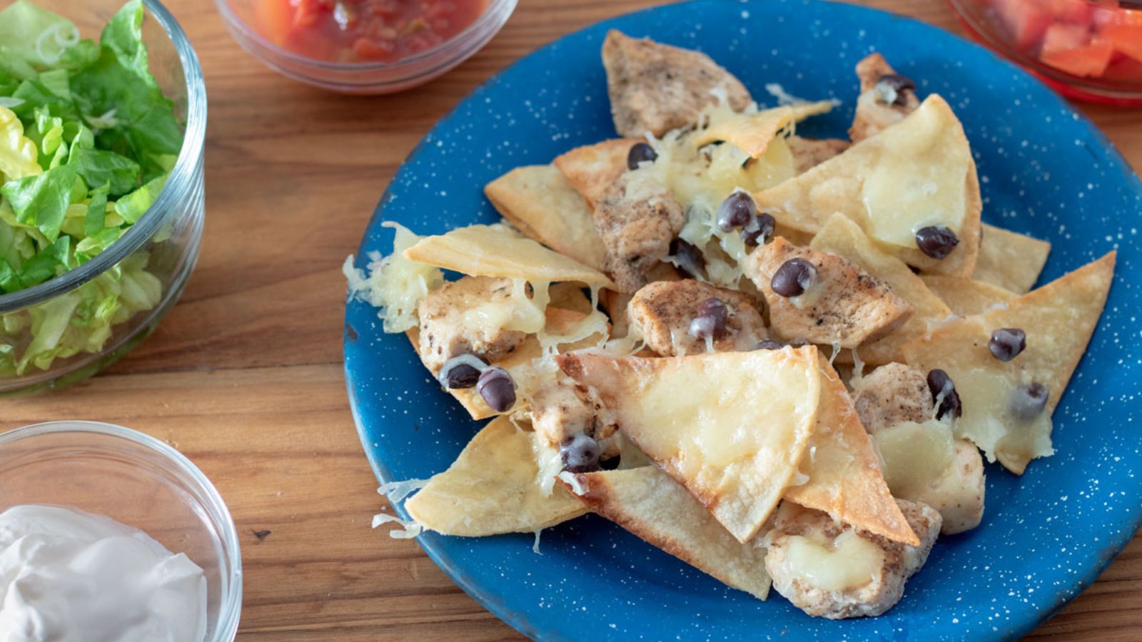 Chicken nachos served on a blue plate with fresh veggies on the side