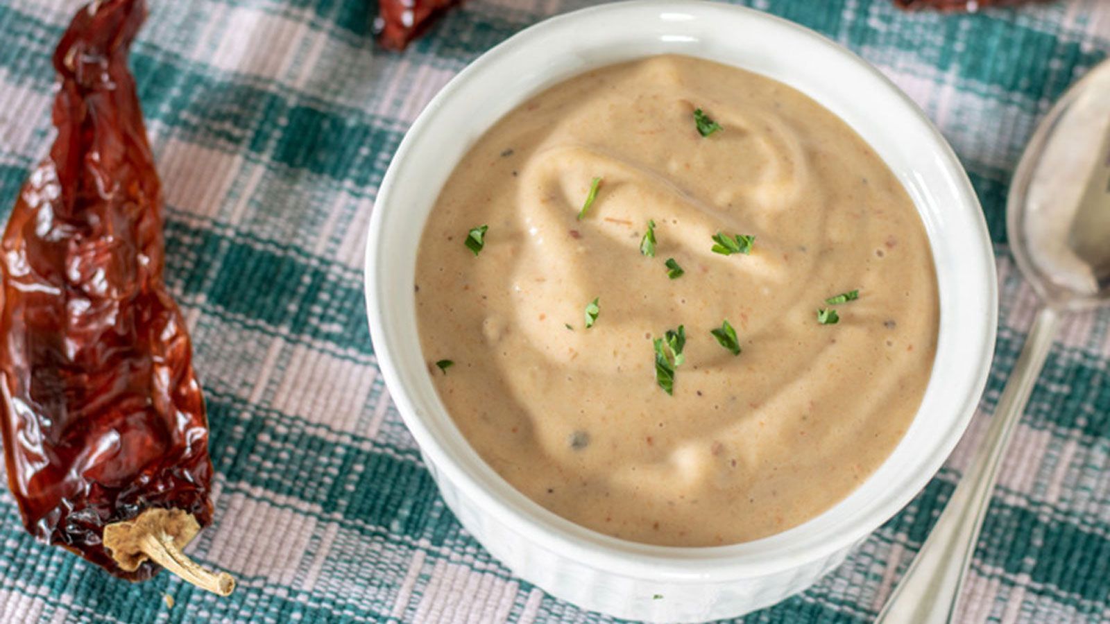 Aioli in white bowl with dried chipotles.