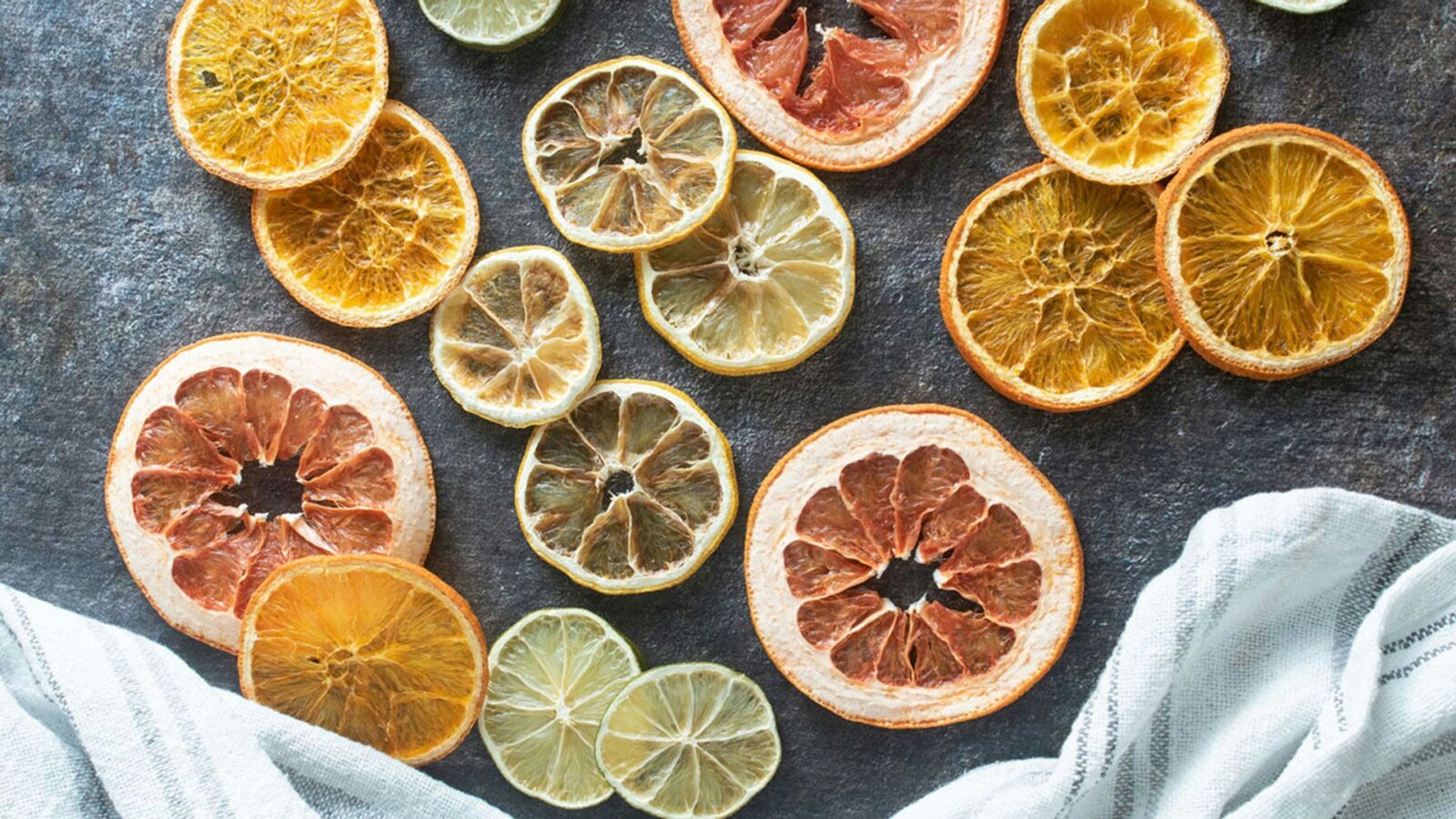 Various dehydrated citrus slices, spread across a dark board.