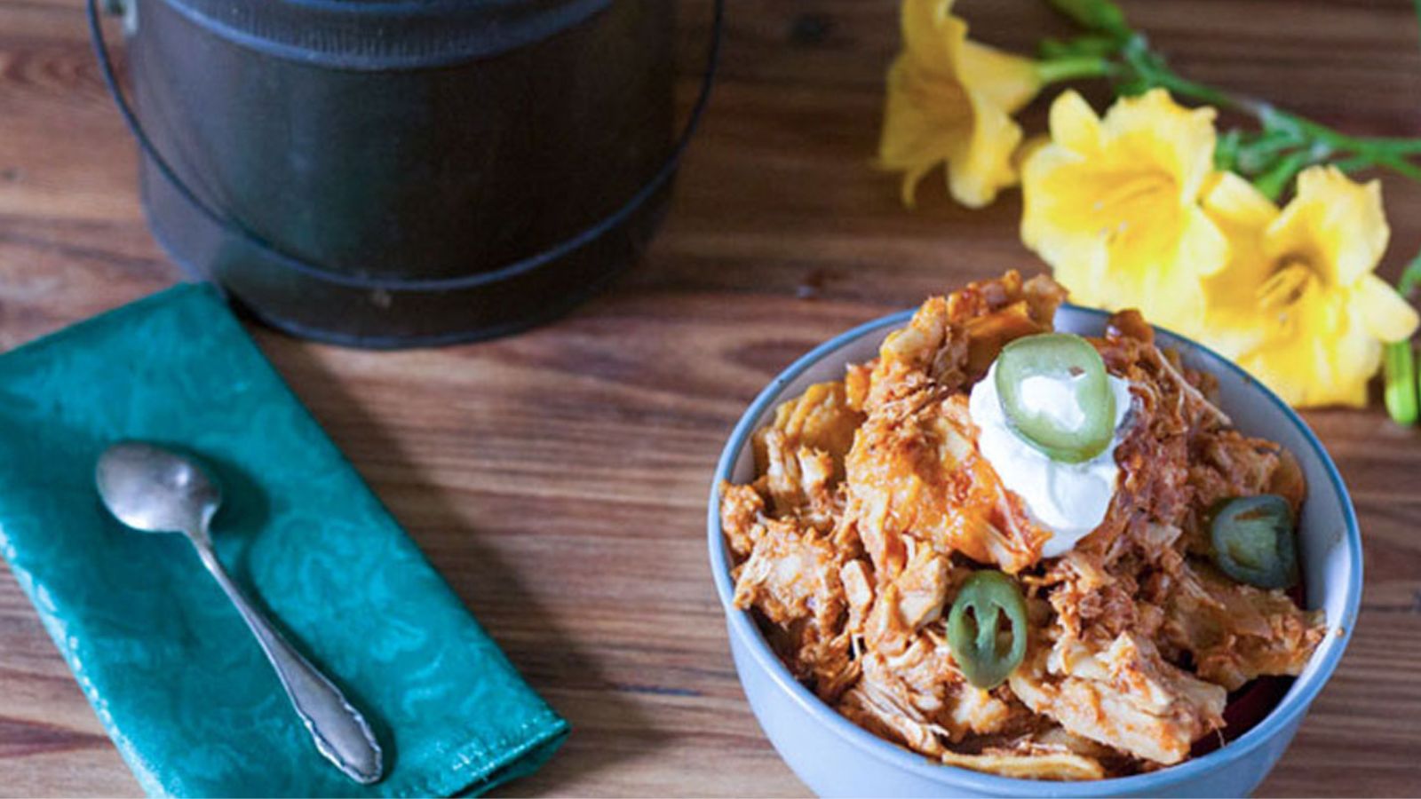 Enchilada casserole in gray bowl garnished with sour crema and jalapeno slices