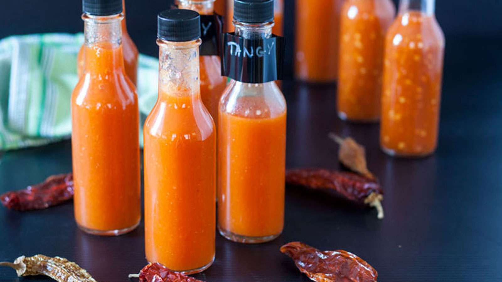 Bottles of hot sauce on a black board. 
