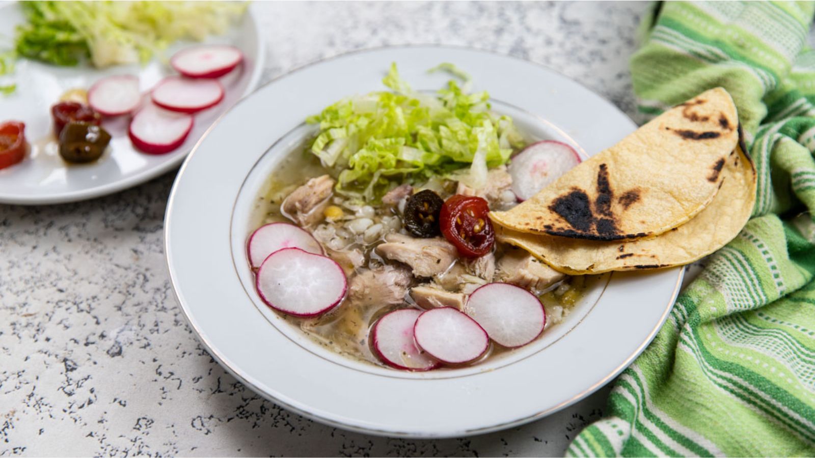 Chicken soup garnished with colorful vegetables and tortillas.