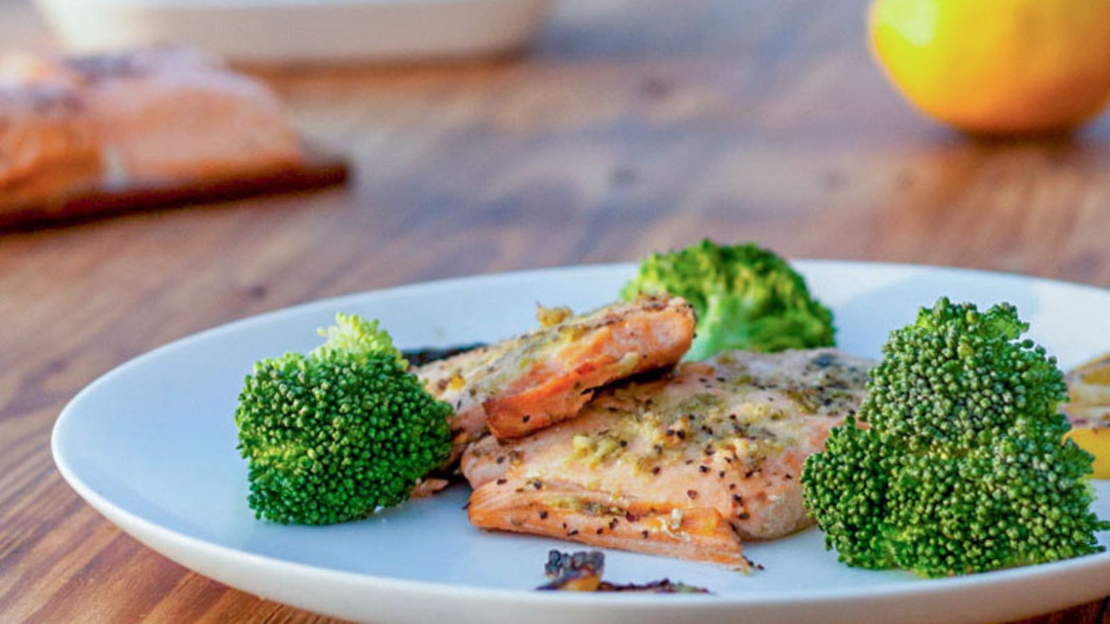 Salmon topped with pesto on white plate with broccoli.