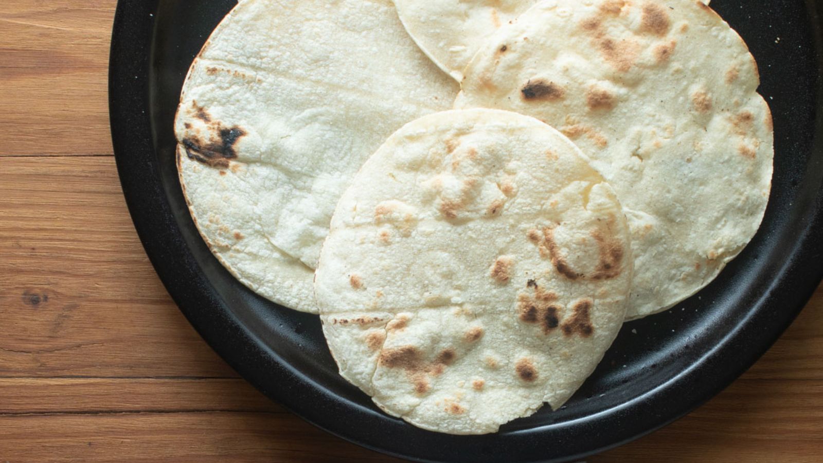 Browned tortillas on a black plate.