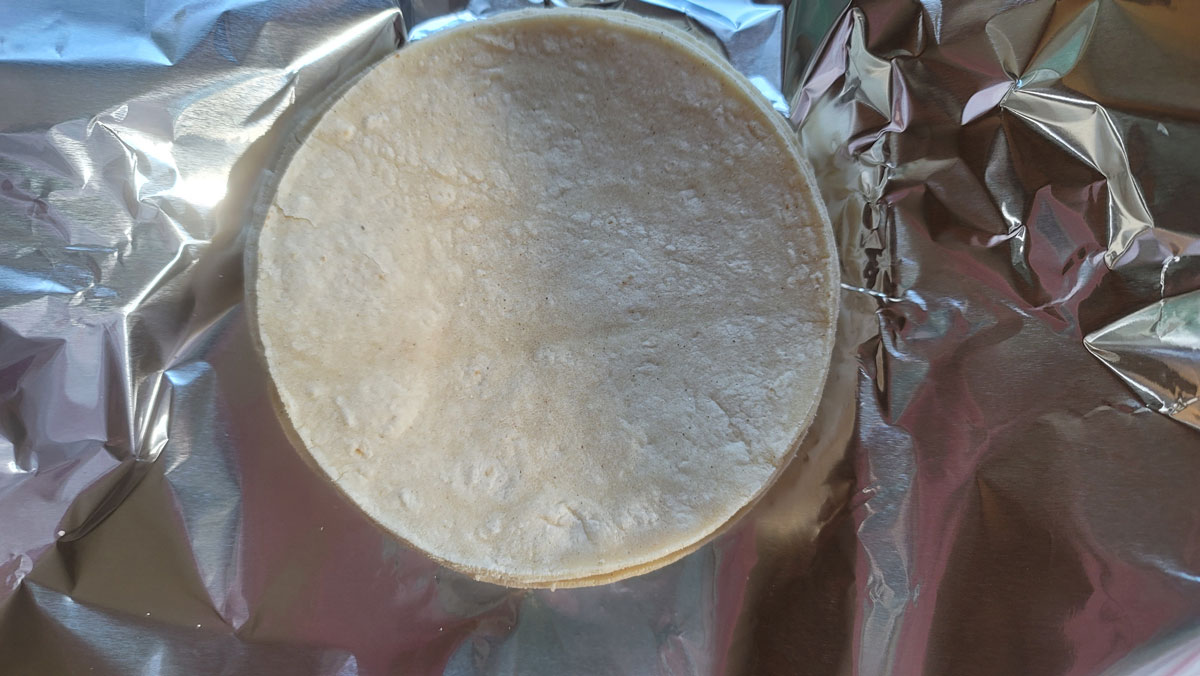 Tortillas in the center of aluminum foil sheet.