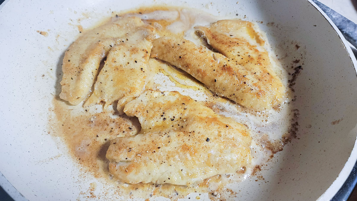 Fish filets browning in skillet.