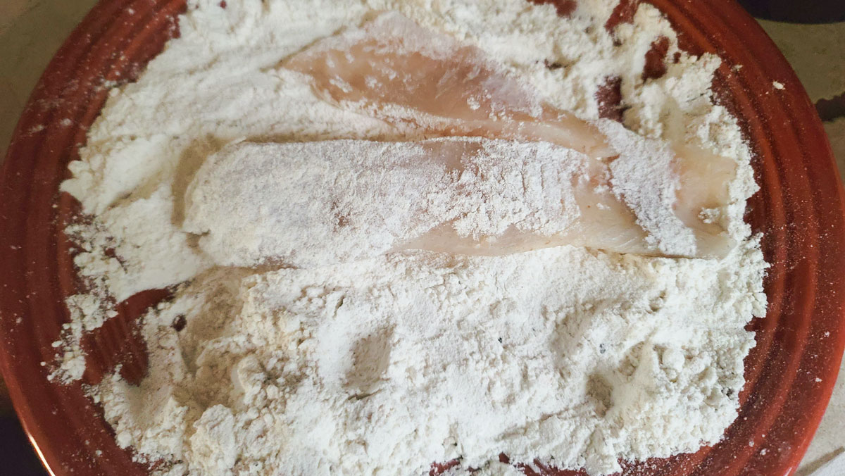 Dredge the fish in the flour mixture.