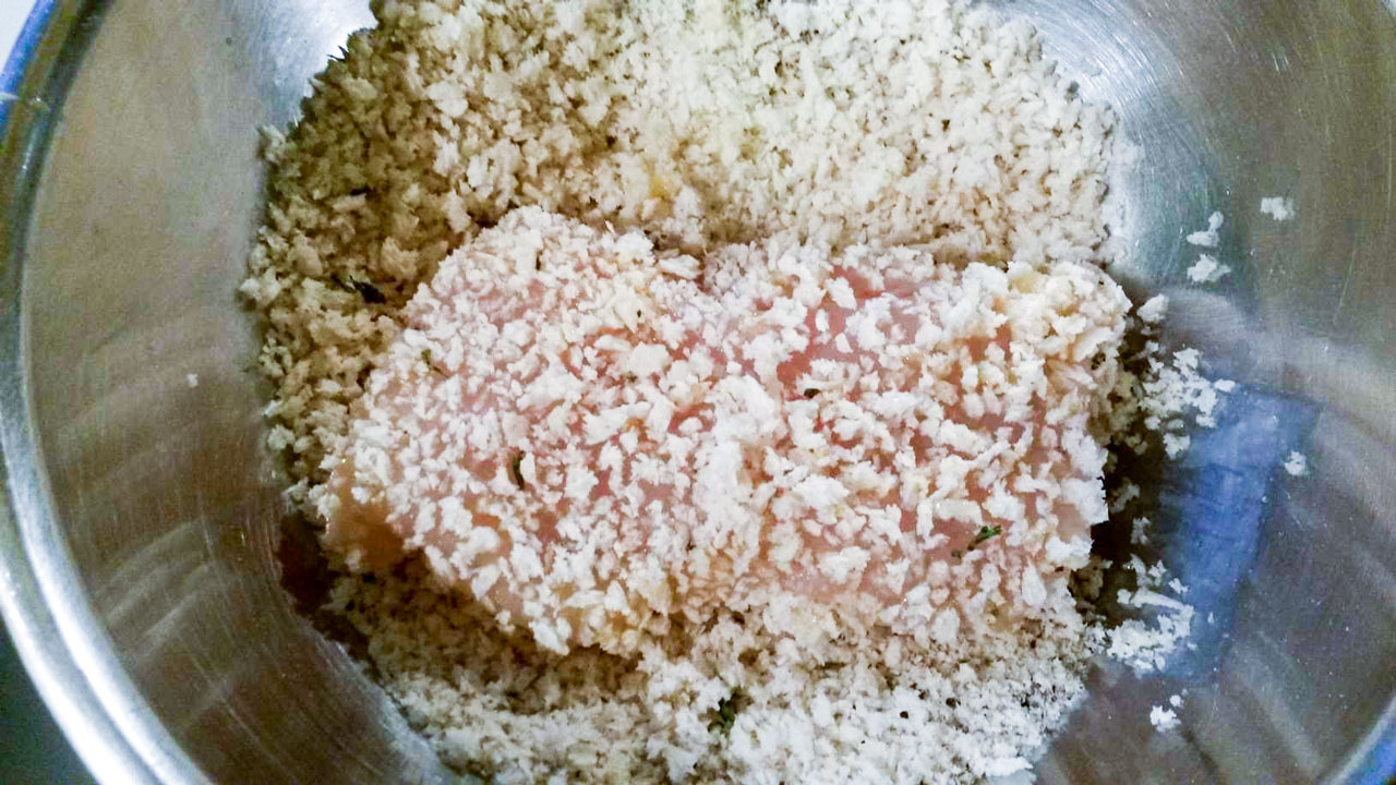 Filet being breaded with bread crumbs.