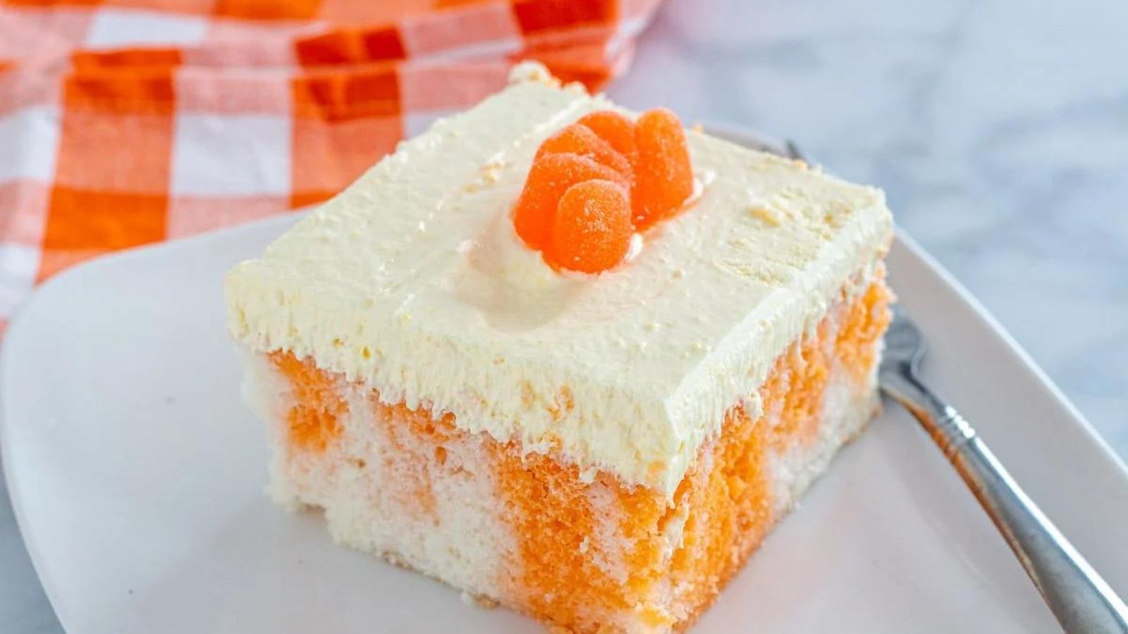 Closeup of square slice of citrus (orange) dreamsicle cake served on a white plate.