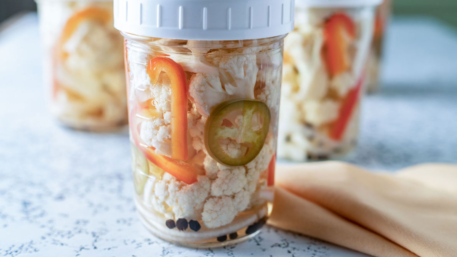 Pickled cauliflower in a jar with peppers and spices.