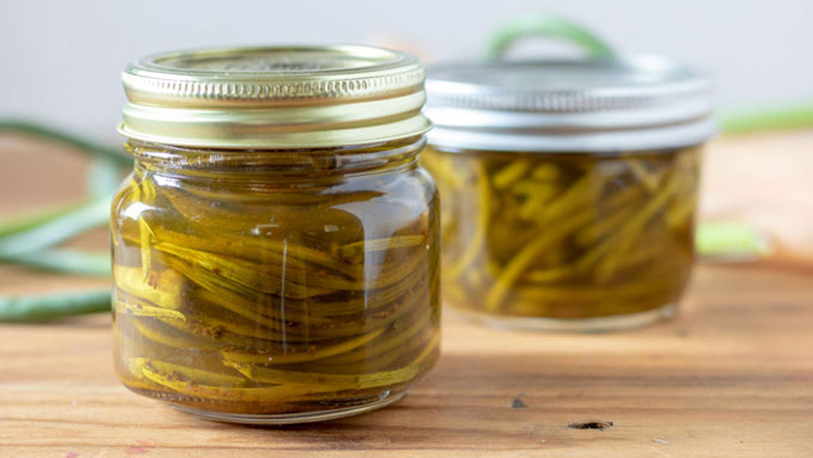 Pickled garlic scapes in jars.