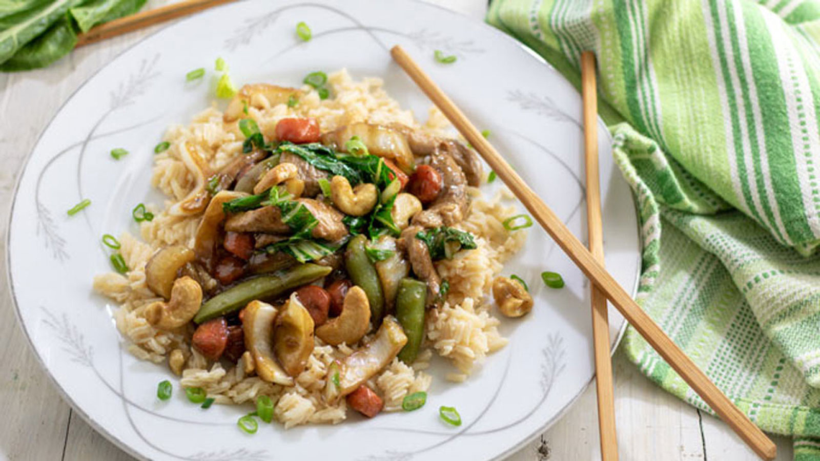Stir fry in a white bowl with chopsticks on the side.